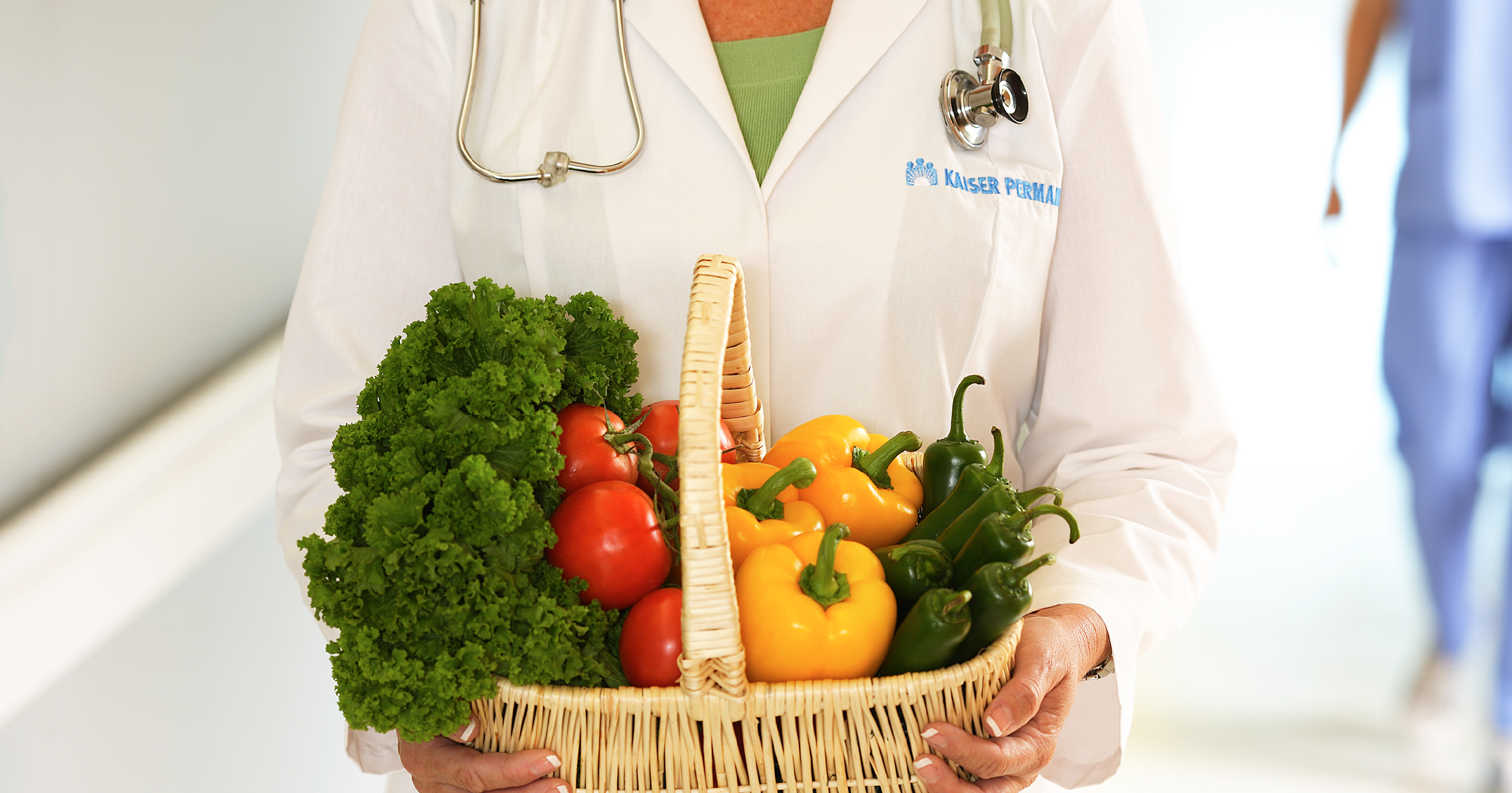Physician holding basket of healthy fruits and vegetables